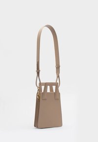 Beżowa torebka crossbody o zorganizowanej konstrukcji, gładkiej skórzanej fakturze, krótkich rączkach u góry i regulowanym długim pasku; zawiera złote akcenty.