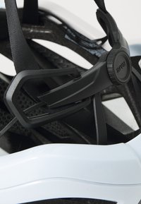 Baskets bleu clair avec une finition brillante, dotées d'une sangle noire réglable et d'accents en mesh, mettant en avant un design moderne et une forme structurée.