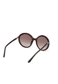 Lunettes de soleil rondes en écaille de tortue avec des verres à dégradé sombre et des branches fines, présentées en angle sur un fond blanc.
