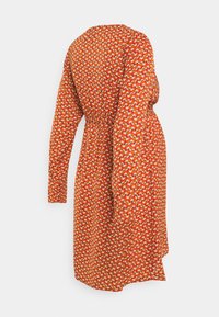 Czerwona sukienka z długimi rękawami i dopasowaną talią, zdobiona kwiatowym wzorem w kolorze żółtym, białym i zielonym na strukturalnym materiale.