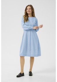 Svetlo modré, dlhé šaty s rovno strihaným strihom, okrúhlym výstrihom a dvoma bočnými vreckami. Ukončené šitým lemom a zhodnými gombíkmi.