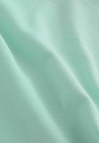 Tela de tono verde menta claro con una textura suave y lisa, ligero brillo, presenta patrones horizontales sutiles y pliegues suaves en caída.