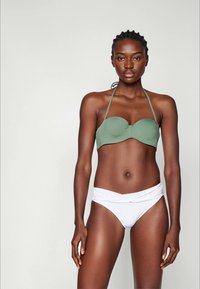 Haut de bikini bandeau vert avec liens tour de cou, associé à un bas de bikini blanc à nouer autour. Texture lisse, design minimaliste.