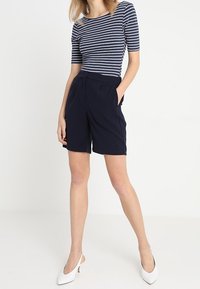 Námořnické skládací šortky se bočními kapsami, spárované s přiléhavým proužkovaným tričkem. Obsahuje kulatý výstřih a krátké rukávy.