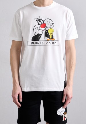 Person wearing a white T-shirt with cartoon characters Sylvester and Tweety and Italian text, paired with black shorts featuring another cartoon.
