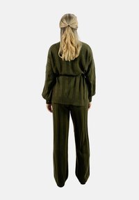 Conjunto de punto verde que presenta un diseño texturizado y estriado. La parte superior tiene un ajuste holgado y los pantalones tienen un estilo de pierna ancha con rayas verticales.