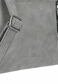 Bolso de cuero gris con textura suave, que presenta una hebilla de metal y una marca grabada. El diseño es rectangular con una estética minimalista.