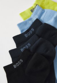 Five pairs of socks in various colors: black, dark blue, light blue, and neon yellow. Each features a ribbed texture and "BOSS" branding on the cuff.