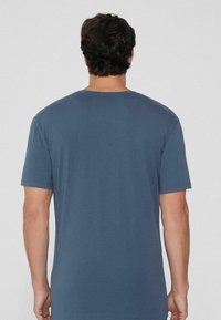 Camiseta de manga corta azul de algodón suave, con cuello redondeado y un corte relajado. Espalda sin costuras, sin patrones ni acentos visibles.