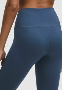 Aukšto liemens, tamsiai mėlyni legginsai, pagaminti iš lygaus, tamprios medžiagos. Pasižymi plokščiais siūlais ir elegantišku, prie kūno priglundančiu dizainu.
