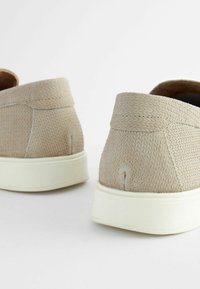 Beige, textúrált, slip-on cipők, szőtt felsőrész, finom varrás és vastag, fehér gumitalp jellemzi őket. Letisztult dizájn, látható márkajelzés nélkül.