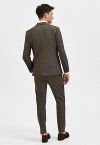 Bruin geruit pak met een getailleerde pasvorm, voorzien van een enkelbreasted jasje en slim-fit broeken, gecombineerd met donkerbruine schoenen.