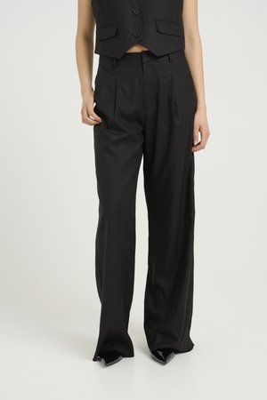 Sorte skreddersydde bukser med høy midje, legg, og en glatt tekstur, kombinert med en cropped vest med knapper og to lommer.