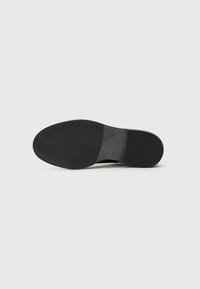Talpa neagră de pantof cu un finisaj din cauciuc neted, formă rotunjită și profil plat; include detalii subtile de branding pe lateral.