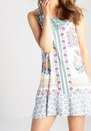 Robe sans manches avec des motifs floraux et géométriques en blanc, bleu et rouge. Dotée d'un col texturé et d'une hemline évasée pour un ajustement décontracté.