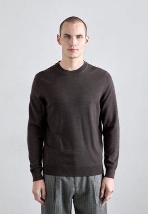 Brown knit sweater with a round neckline and long sleeves, paired with gray, vertically striped high-waisted trousers.