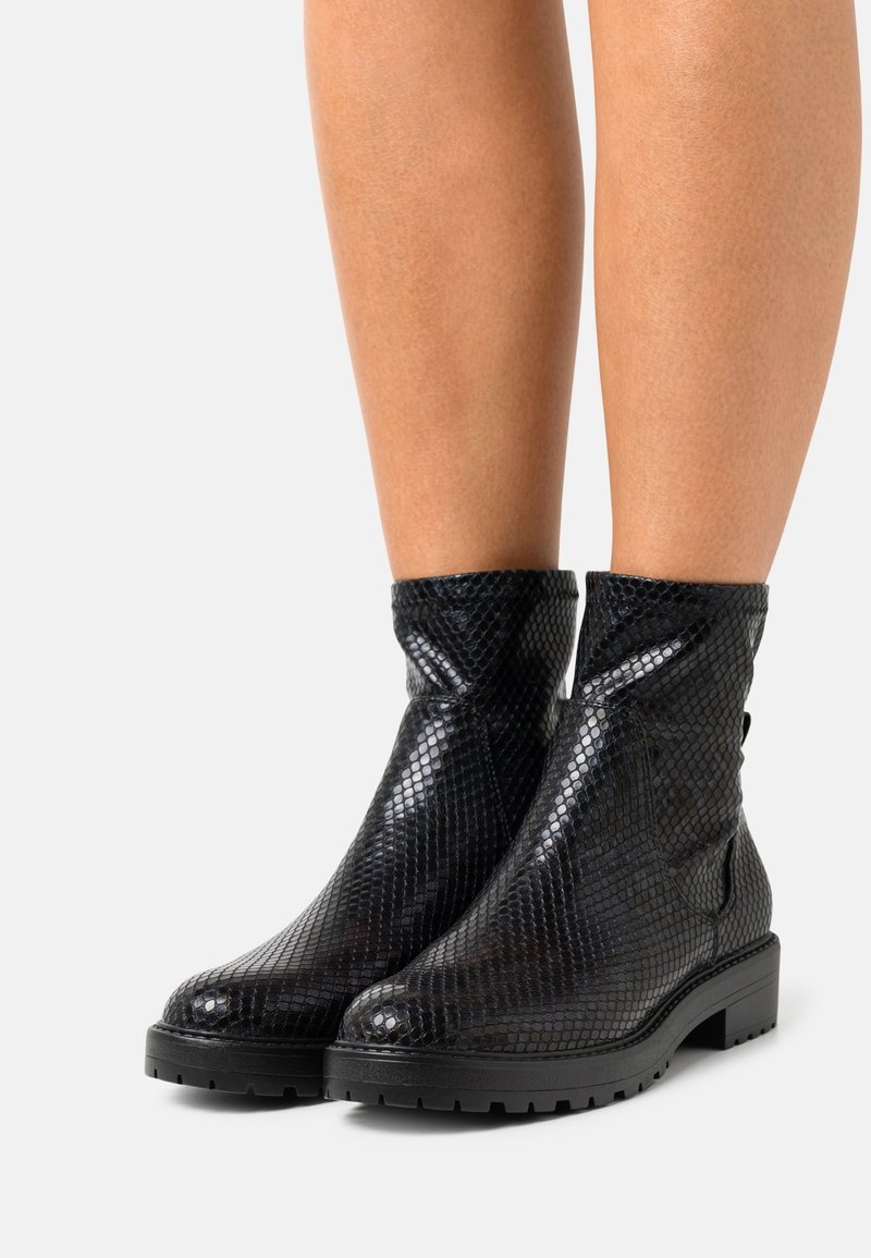 Botines negros de tobillo hechos de un material brillante y texturizado con un patrón de piel de serpiente, que cuentan con una suela robusta y una abertura holgada.