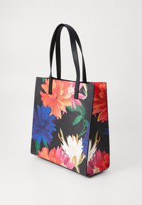 Handlenett med svart bakgrunn, prydet med livlige blomster mønstre i rosa, oransje, hvitt og blått, med sorte lærhåndtak.
