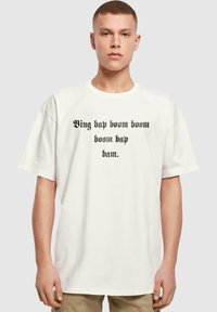 Hvid bomulds T-shirt med korte ærmer, der har sort tekst, som lyder "Bing bap boom boom boom bap bam" i en stiliseret skrifttype.