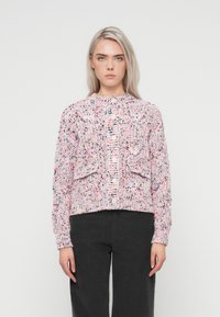 Pletený svetr v růžové barvě s texturovanými vzory a vícebarevnými tečkami. Má kulatý výstřih, zapínání na knoflíky vpředu a dvě přední kapsy.