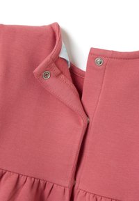 Vestido de algodón rosa con un dobladillo con volantes, que presenta un cierre de botón a presión en el escote y una textura suave. Acentuado con una etiqueta en el interior.