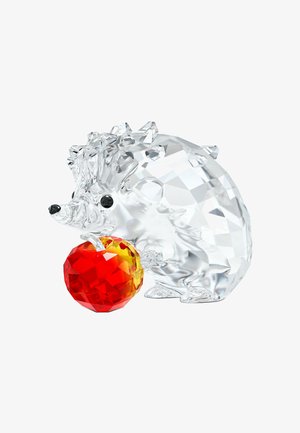 Klarer facettierter Kristall-Igel, der einen roten und gelben facettierten Kristallapfel auf weißem Hintergrund hält.