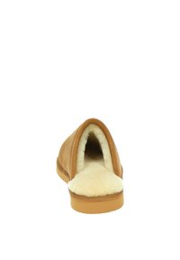 Bruine suède pantoffel met een zachte crème schapenwol voering, open achterkant en rubbere zool. Minimalistisch ontwerp zonder versieringen.