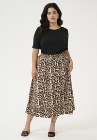 Haut noir à manches courtes associé à une jupe longue jusqu'aux chevilles imprimée léopard beige, dotée d'une taille élastique et d'une silhouette fluide.