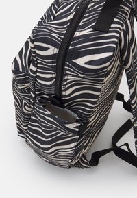 Svart och vit zebramönstrad ryggsäck med ett stort huvudfack, frontdragkedja och sidoficka. Tillverkad av slitstarkt tyg med justerbara remmar.