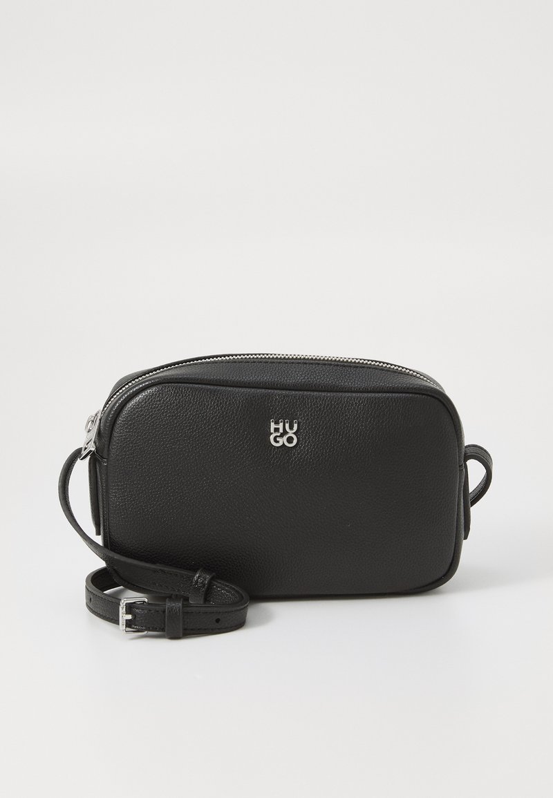 Black soft leather crossbody bag with a zip closure, silver logo, adjustable strap, and rectangular shape. Textured surface detail.