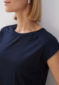 Námořnický top s krátkým rukávem vyrobený z hladké tkaniny, s kulatým výstřihem a jemnými akcenty na ramenních švech.