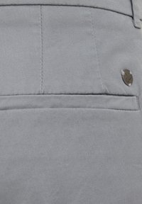 Sive hlače iz tkanine z gladko teksturo, ravnim krojem in zadnjim žepom z okroglo kovinsko logo akcentom.
