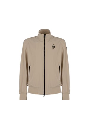 Giacca beige croppata con colletto alto, zip frontale, due tasche laterali, polsini elasticizzati e una leggera lucentezza. Presenta una patch con il logo sul petto.