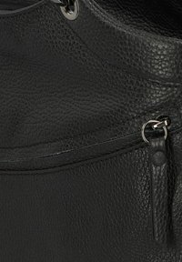 Sac à main en cuir noir avec une surface texturée, poche zippée et un accent matériel circulaire pour la fermeture. Fini lisse avec des coutures détaillées.