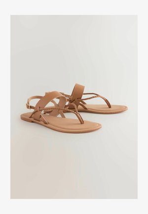 Tan platta sandaler med en minimalistisk design, som har flätade remmar och ett tåsak. Slät material och enkel hårdvara framhäver utseendet.