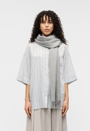 Hellgraues, gestreiftes, oversized Hemd mit Knopfleiste und kurzen Ärmeln; kombiniert mit einem weichen grauen Schal mit Fransen.