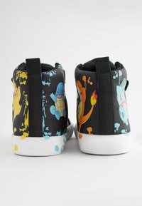 Schwarze High-Top-Schuhe zeigen auf beiden Seiten bunte Charakterdrucke, mit einer weißen Gummisohle und schwarzem Akzentstoff in der Nähe des Knöchels.