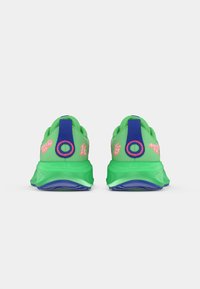 Πράσινα αθλητικά παπούτσια με υφή από δικτυωτό υλικό, μπλε λεπτομέρειες και ροζ λογότυπο. Η σόλα είναι έντονα αφρώδης με ορατό πέλμα.