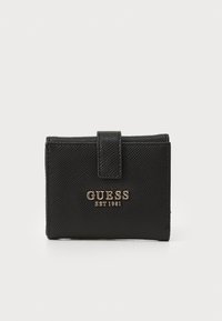 Juodas piniginė su tekstūruotu paviršiumi, turinti priekinį paspaudimo užsegimą ir auksinį logotipą "GUESS EST 1981" iškilmingai įspaustą priekyje.