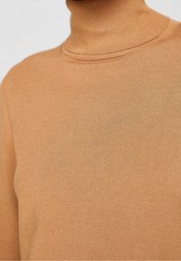 Svetr s vysokým límcem v teplé jantarové barvě, vyrobený z měkké látky s hladkou texturou. Obsahuje přiléhavý design a detaily s žebrováním na límci.