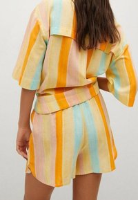 Gestreiftes zweiteiliges Outfit mit kurzen Ärmeln in Pastellfarben wie Orange, Rosa und Blau, mit lockerem Schnitt und weicher Textur.