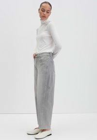 Gray high-waisted jeans with a loose fit, crafted from denim fabric, featuring five-pocket design and subtle stitching details, paired with a white turtleneck.