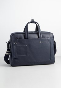 Borsa per laptop in pelle blu navy con due manici superiori, tracolla rimovibile, tasca frontale con zip e finitura testurizzata.