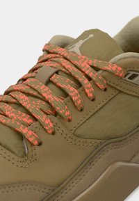 Χακί αθλητικά παπούτσια με υφασμάτινη υφή, χοντρές πορτοκαλί και καφέ λωρίδες, και ανοιχτόχρωμο καφέ σόλα με ορατή ραφή.