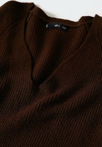 Pull en tricot côtelé brun foncé avec col en V et étiquette de marque visible à l'intérieur du col.