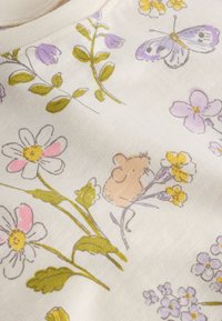 Tela suave con delicados patrones florales, un pequeño ratón beige y una mariposa morada sobre un fondo crema.