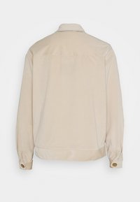 Giacca beige con colletto, maniche lunghe e polsini con bottoni. Tessuto liscio con silhouette ampia e dettaglio di yoke sul retro.