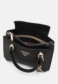Sac à main Guess noir avec double poignée, hardware doré, compartiment zippé et fermeture à rabat, présenté ouvert pour révéler les poches intérieures.