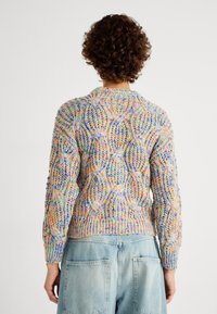 Bunt gestrickter Pullover mit strukturiertem Muster, geripptem Saum und Bündchen. Das Material wirkt weich und der Schnitt entspannt.