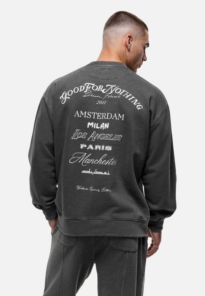 Fleece sweatshirt in donkergrijs, met een grote witte afbeelding met stadsnamen en "GOOD FOR NOTHING" op de achterkant, met ribgebreide cuffs en zoom.
